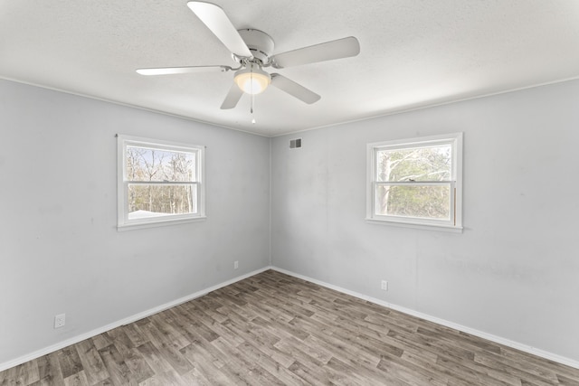 unfurnished room with baseboards, visible vents, ceiling fan, wood finished floors, and a textured ceiling