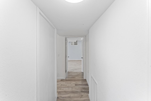 hallway featuring light wood-type flooring and visible vents