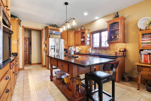 kitchen with light tile patterned floors, backsplash, appliances with stainless steel finishes, glass insert cabinets, and a sink