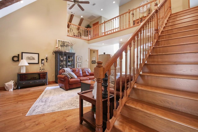 stairway featuring a ceiling fan, recessed lighting, a high ceiling, and wood finished floors