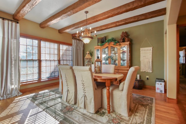 dining area featuring an inviting chandelier, beam ceiling, and wood finished floors