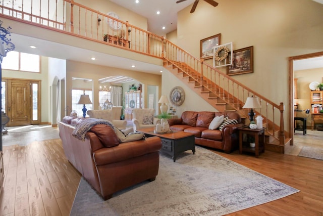 living room with a towering ceiling, plenty of natural light, stairs, and wood finished floors