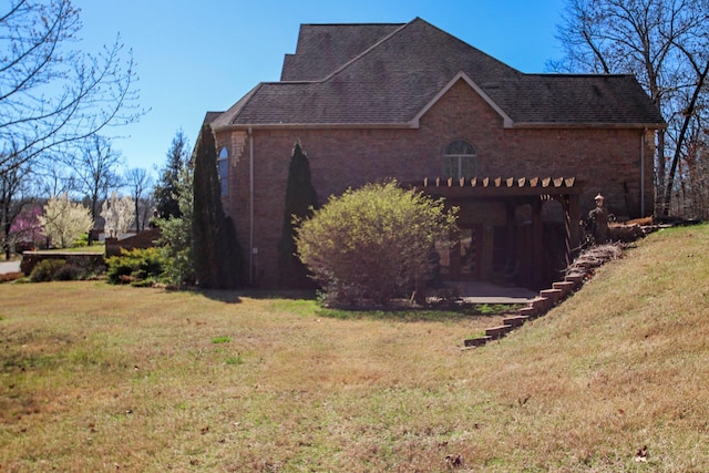 view of side of home with brick siding, a patio area, and a yard