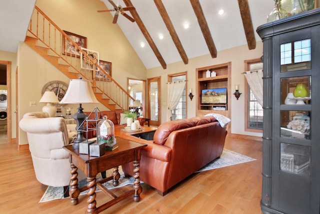 living room featuring high vaulted ceiling, beam ceiling, a healthy amount of sunlight, and stairs