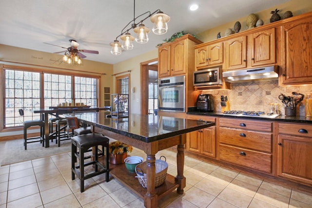 kitchen featuring appliances with stainless steel finishes, light tile patterned flooring, backsplash, and under cabinet range hood