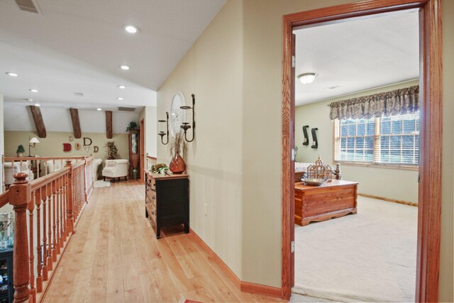 corridor featuring visible vents, baseboards, lofted ceiling, light wood-type flooring, and recessed lighting