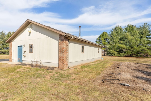 view of side of property with brick siding and a lawn