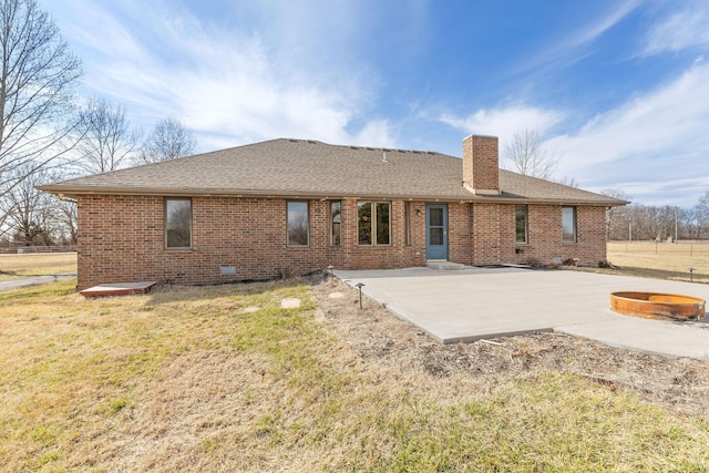 rear view of property with a fire pit, brick siding, a lawn, a chimney, and a patio area