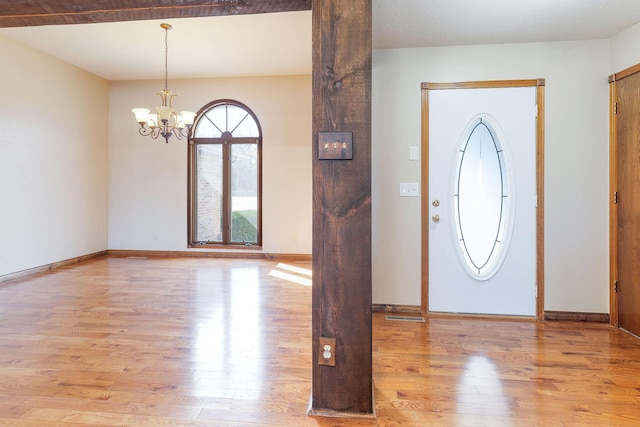 foyer entrance featuring an inviting chandelier, baseboards, and wood finished floors