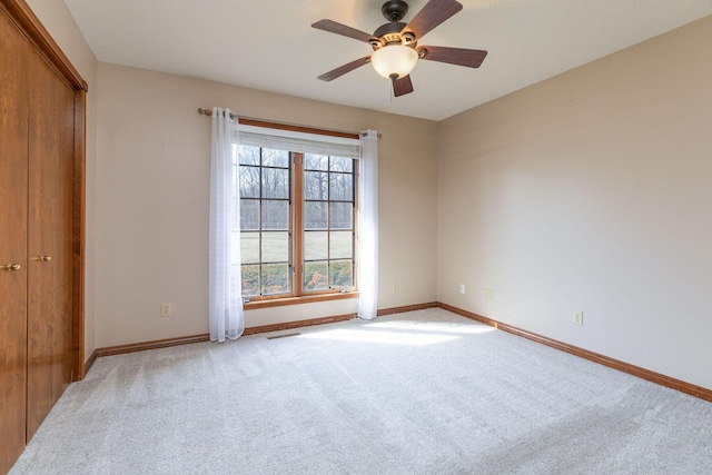 spare room with light carpet, visible vents, baseboards, and a ceiling fan