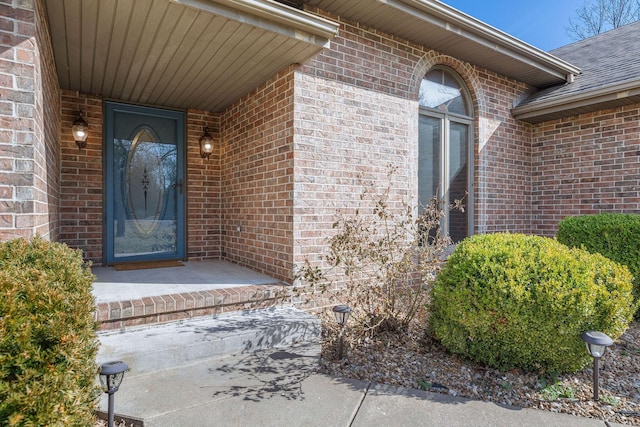 property entrance with brick siding and roof with shingles