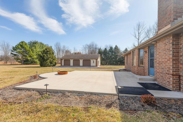 view of patio featuring a garage, a fire pit, and an outbuilding