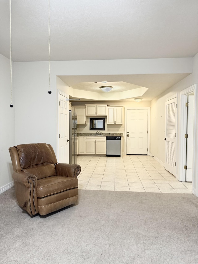 living room featuring light carpet, baseboards, a tray ceiling, and light tile patterned flooring