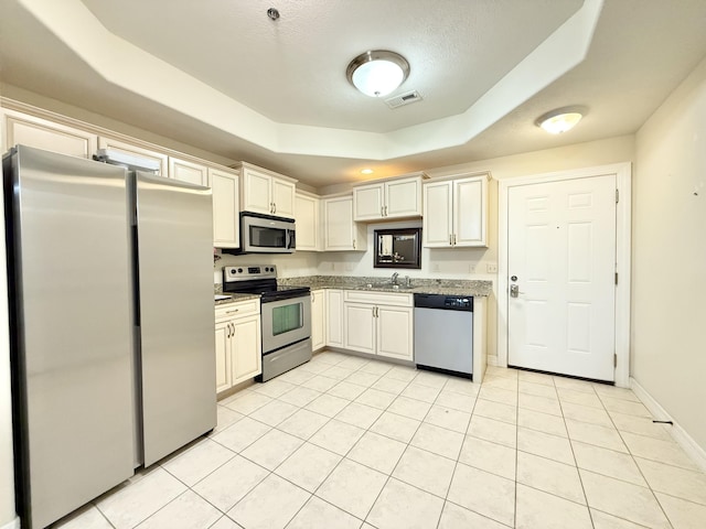 kitchen with light tile patterned floors, visible vents, a raised ceiling, baseboards, and appliances with stainless steel finishes