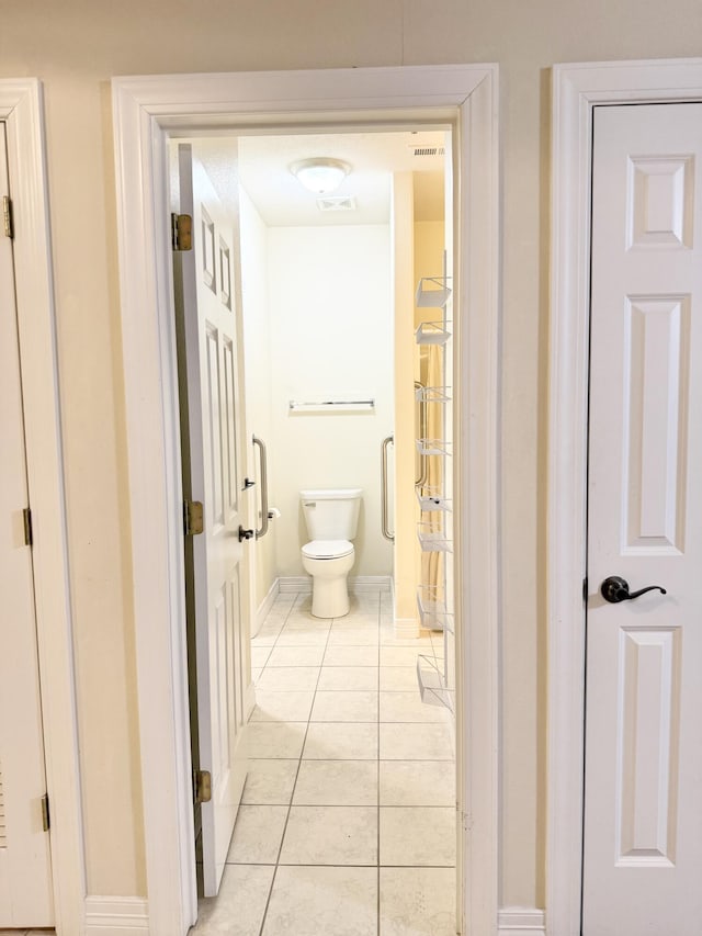 hallway with visible vents, baseboards, and light tile patterned floors