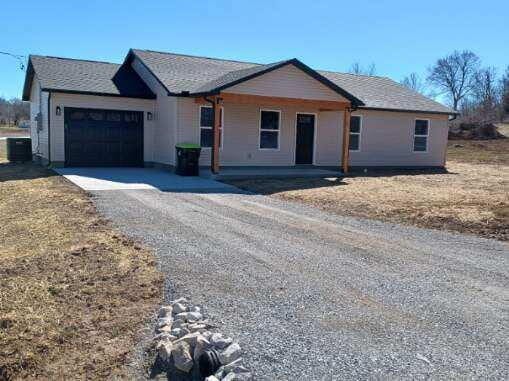 ranch-style home with a garage, driveway, and central AC unit