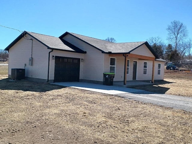 ranch-style home with a garage, cooling unit, driveway, and a porch