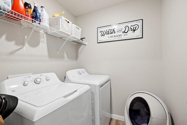 laundry area featuring laundry area, washer and clothes dryer, baseboards, and wood finished floors