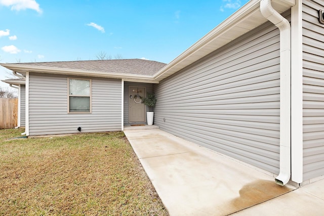 entrance to property featuring a yard and fence