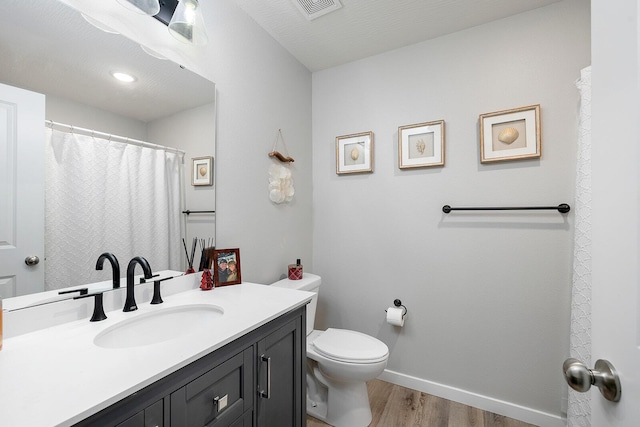 full bathroom with toilet, wood finished floors, vanity, visible vents, and baseboards