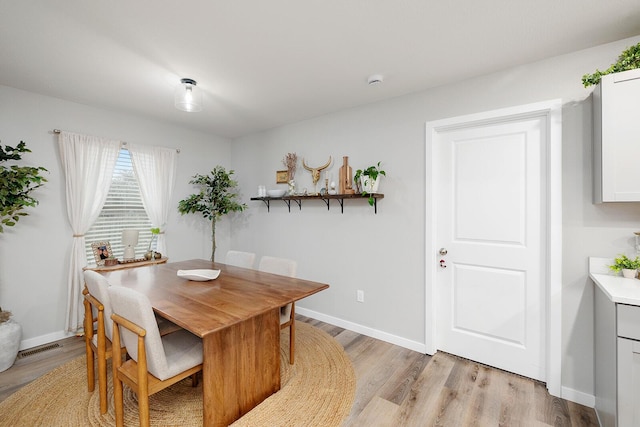 dining space with visible vents, light wood-style flooring, and baseboards