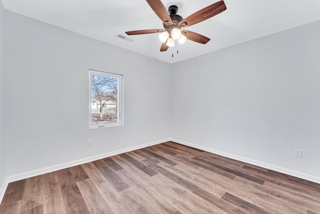 empty room with a ceiling fan, visible vents, baseboards, and wood finished floors