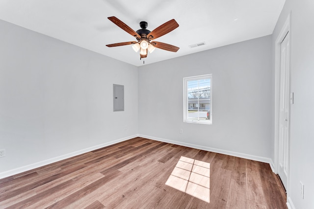 spare room with visible vents, ceiling fan, wood finished floors, electric panel, and baseboards