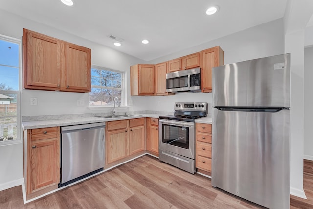 kitchen featuring a sink, light countertops, appliances with stainless steel finishes, light wood-type flooring, and light brown cabinetry