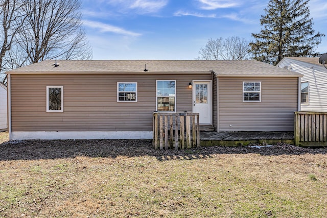 rear view of house with a shingled roof, a yard, and a deck