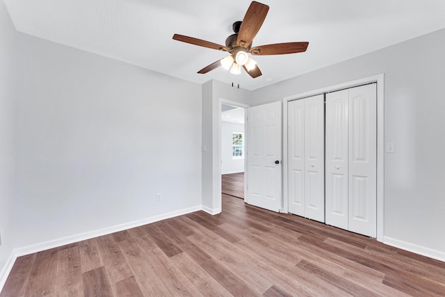 unfurnished bedroom featuring ceiling fan, a closet, wood finished floors, and baseboards