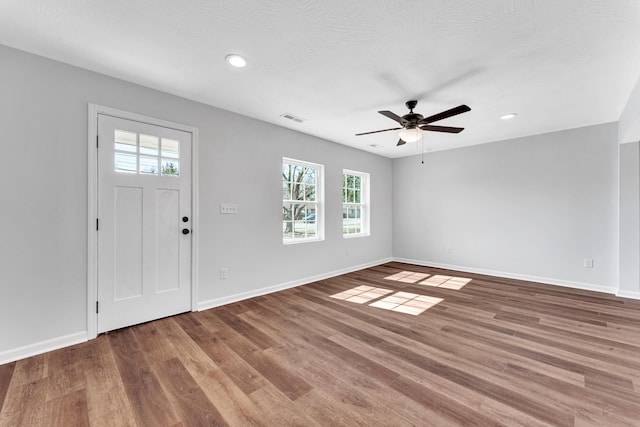 foyer with baseboards, visible vents, ceiling fan, and wood finished floors