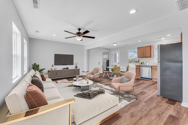 living area with light wood finished floors, visible vents, and recessed lighting