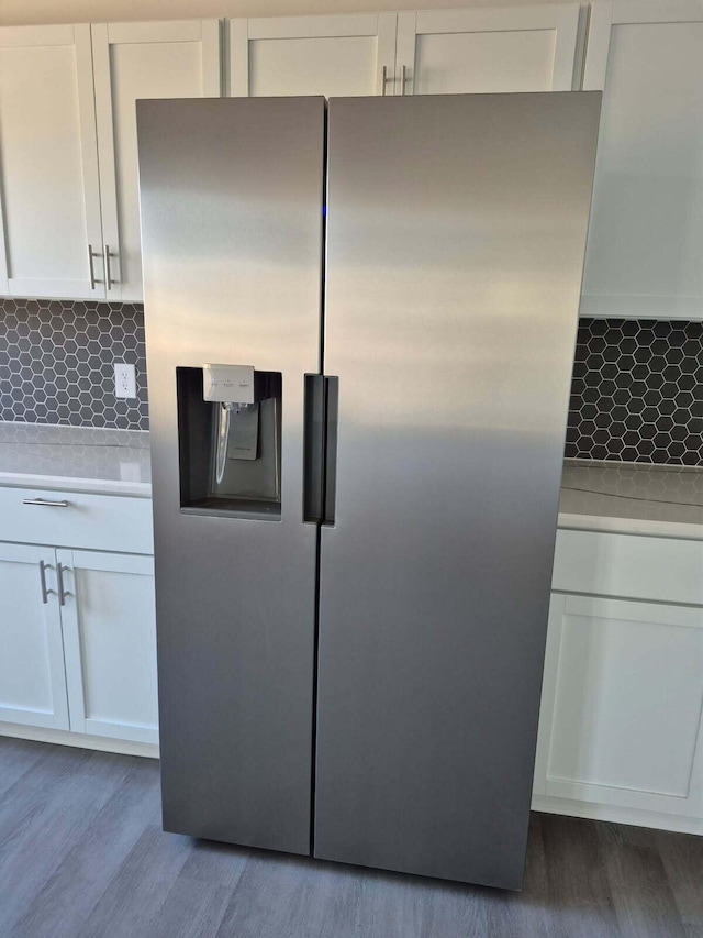 kitchen with wood finished floors, light countertops, stainless steel fridge with ice dispenser, and white cabinetry