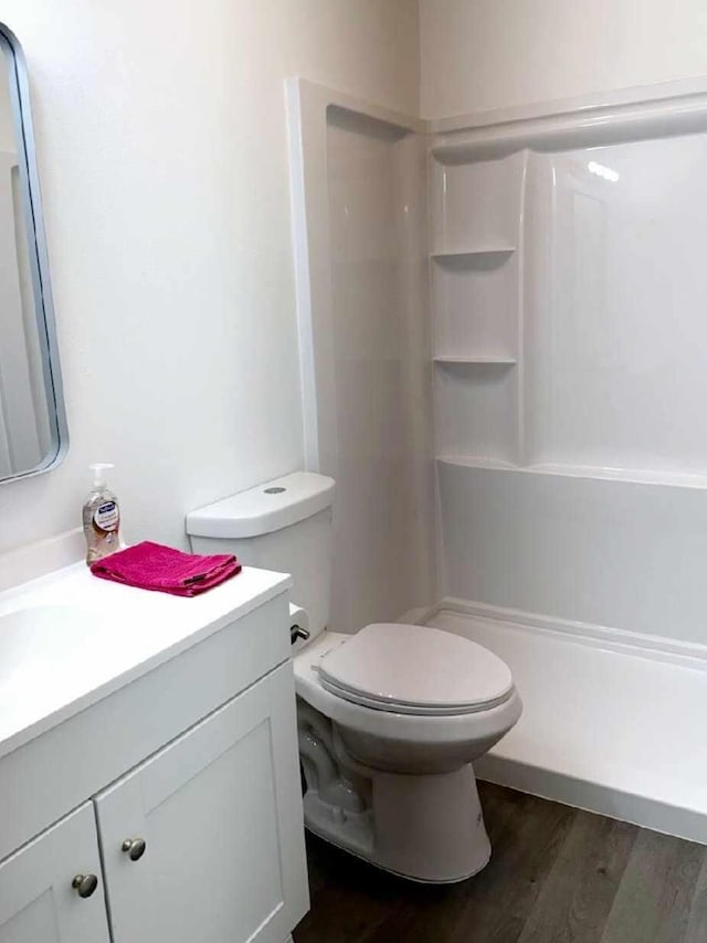 bathroom with toilet, a shower stall, wood finished floors, and vanity