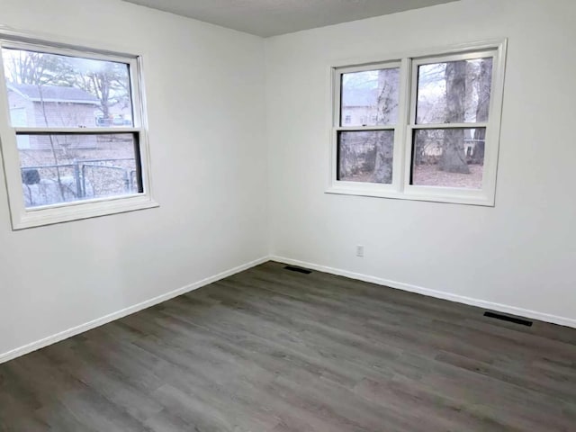 spare room featuring visible vents, baseboards, and wood finished floors