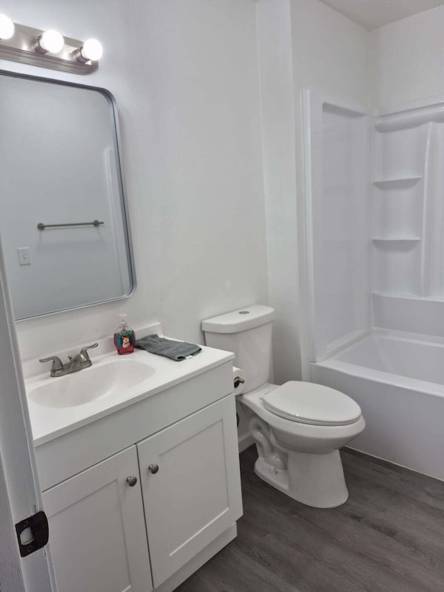 bathroom featuring toilet,  shower combination, wood finished floors, and vanity