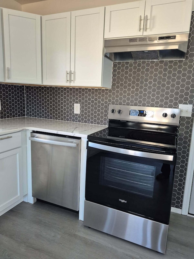 kitchen featuring backsplash, appliances with stainless steel finishes, white cabinets, wood finished floors, and under cabinet range hood