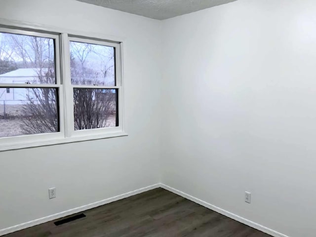 unfurnished room featuring a healthy amount of sunlight, baseboards, and dark wood-type flooring