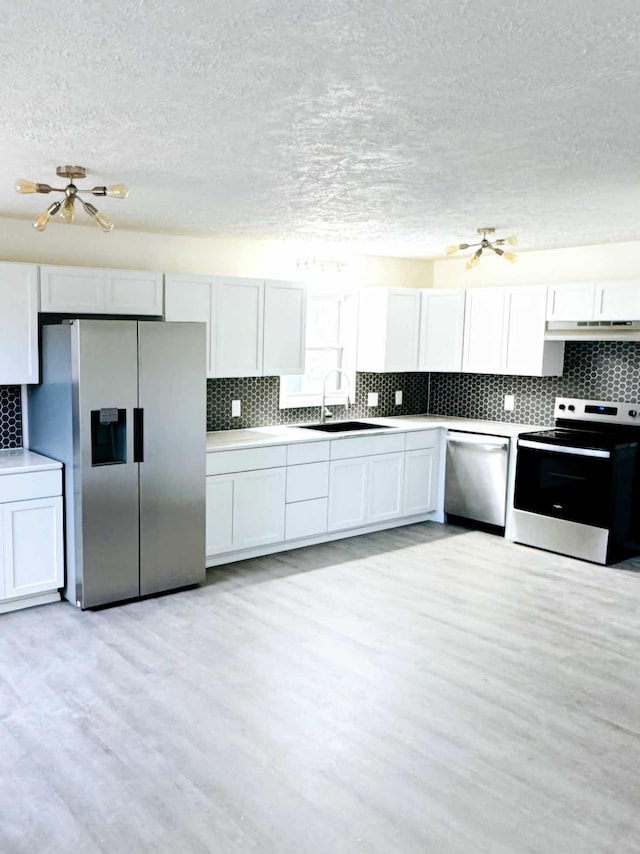 kitchen with light wood finished floors, tasteful backsplash, appliances with stainless steel finishes, and a sink