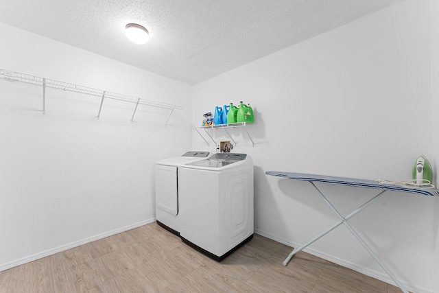 laundry room featuring light wood finished floors, a textured ceiling, laundry area, independent washer and dryer, and baseboards