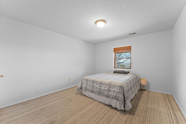 bedroom featuring a textured ceiling, carpet, visible vents, and baseboards