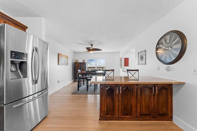 kitchen featuring a peninsula, light wood finished floors, stainless steel refrigerator with ice dispenser, and a textured ceiling