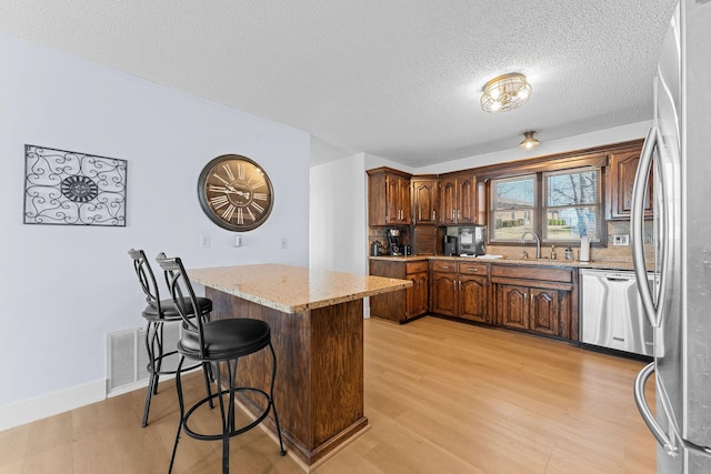 kitchen featuring light wood-style flooring, visible vents, appliances with stainless steel finishes, and a sink