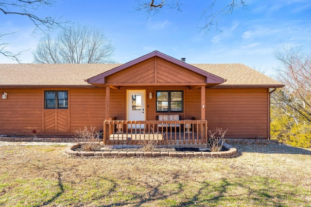 view of front of home with covered porch, a shingled roof, and a front yard