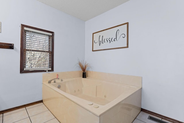 bathroom with a textured ceiling, visible vents, baseboards, a jetted tub, and tile patterned floors