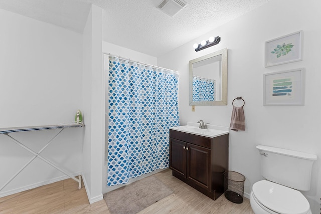 full bath featuring visible vents, toilet, vanity, a textured ceiling, and wood finished floors