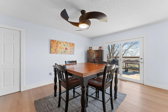 dining room featuring light wood-style floors, baseboards, visible vents, and a ceiling fan