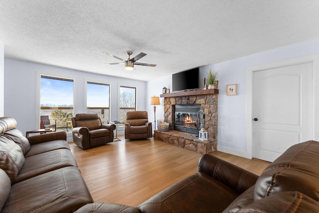 living area featuring a textured ceiling, a fireplace, wood finished floors, and a ceiling fan