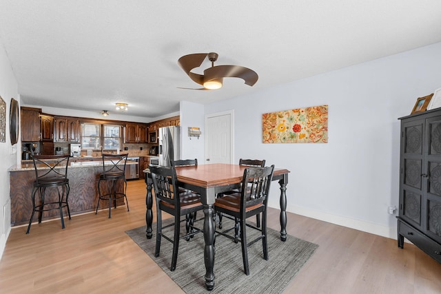 dining space with light wood-style floors, ceiling fan, and baseboards