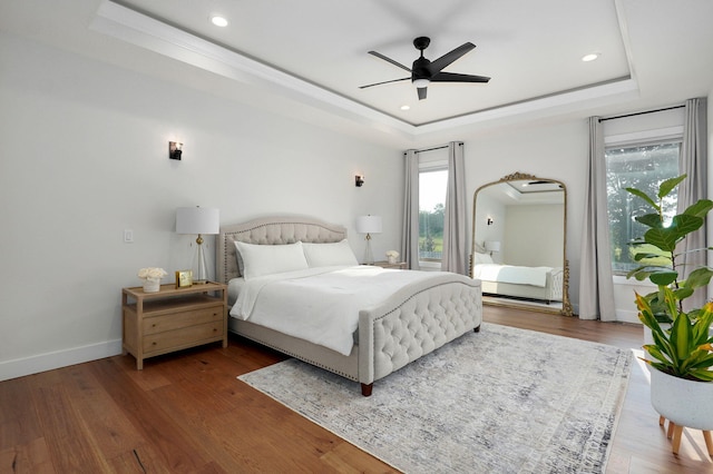 bedroom with baseboards, a tray ceiling, wood finished floors, and recessed lighting